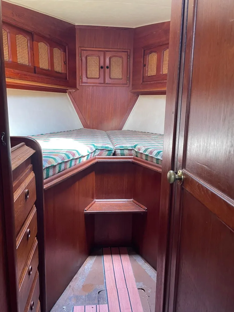 Slide: The Image of 1978 Islander Freeport 41 Ketch cabin interior with wood paneling and striped bedding. - 29