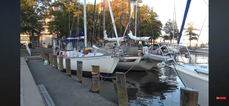 Slide: The Image of 1978 Islander Freeport 41 Ketch docked at a marina with surrounding boats and trees. - 4