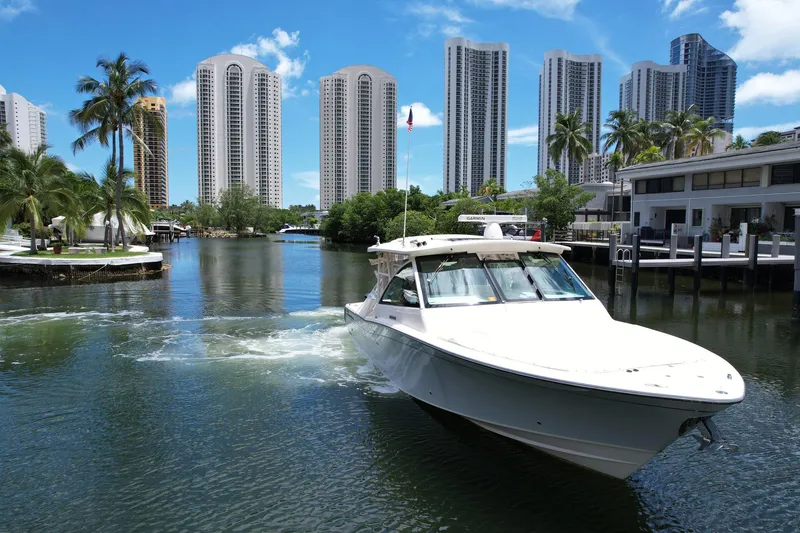 Slide: The Image of 2017 Grady-White Freedom 375 boat cruising in a city canal with skyscrapers and palm trees. - 5