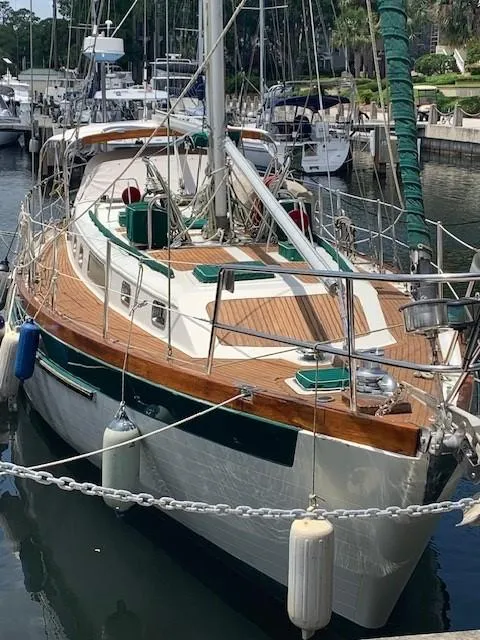 Slide: The Image of 1988 Slocum 43 sailboat docked in marina, featuring wooden deck and green accents. - 1