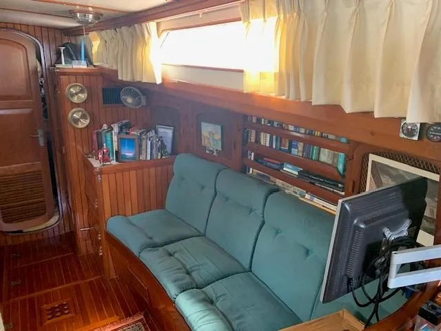 Slide: The Image of Cozy interior of 1988 Slocum 43 sailboat with wood paneling and green sofa. - 18