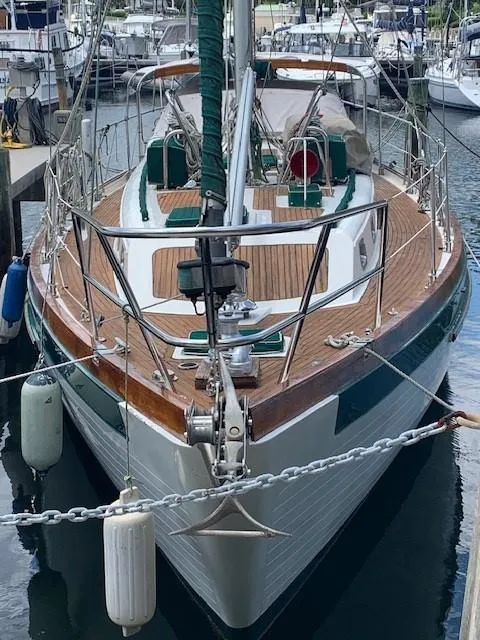 Slide: The Image of 1988 Slocum 43 sailboat docked in marina, featuring wooden deck and green accents. - 2