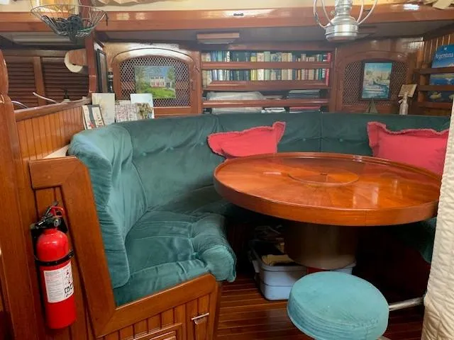 Slide: The Image of Cozy 1988 Slocum 43 yacht interior with green seating, wooden table, and bookshelf. - 22