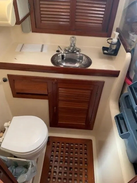 Slide: The Image of 1988 Slocum 43 yacht bathroom with sink, toilet, and wooden cabinetry. - 24