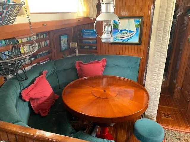Slide: The Image of Cozy 1988 Slocum 43 yacht interior with round wooden table, teal seating, and nautical decor. - 25