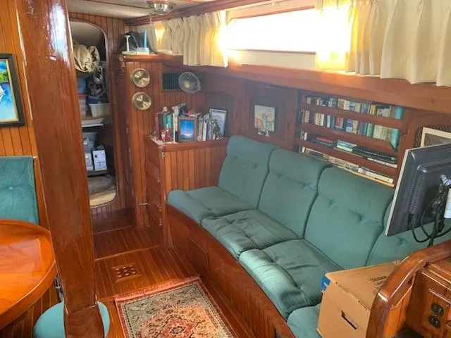 Slide: The Image of Cozy interior of 1988 Slocum 43 sailboat with green sofa and wooden paneling. - 26