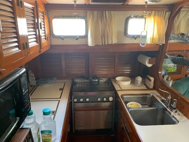 Slide: The Image of 1988 Slocum 43 yacht kitchen with stove, sink, and wooden cabinetry. - 36