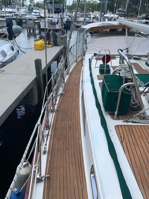 Slide: The Image of 1988 Slocum 43 sailboat docked at marina, featuring teak deck and green sail covers. - 7