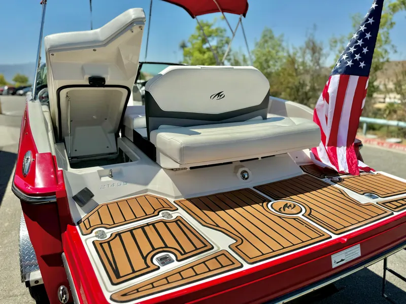 Slide: The Image of 2013 Monterey 214 SS boat with American flag, featuring teak-style deck and seating. - 8