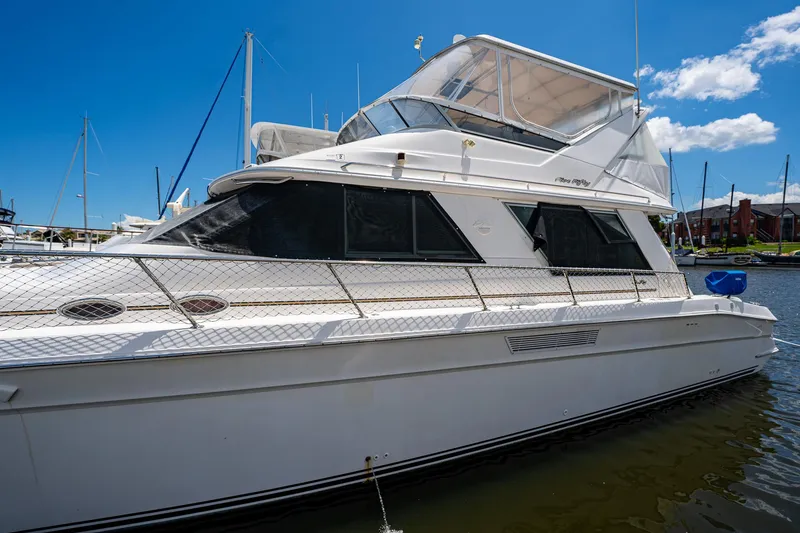 Slide: The Image of 1995 Sea Ray 550 Sedan Bridge yacht docked in marina under blue sky. - 6