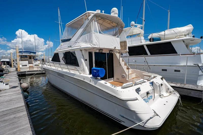 Slide: The Image of 1995 Sea Ray 550 Sedan Bridge yacht docked at marina under clear blue sky. - 7