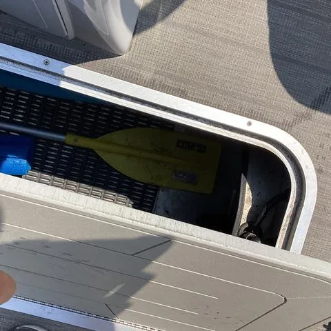 Slide: The Image of Storage compartment on 2019 Godfrey Sw2286SB boat with a yellow paddle inside. - 12