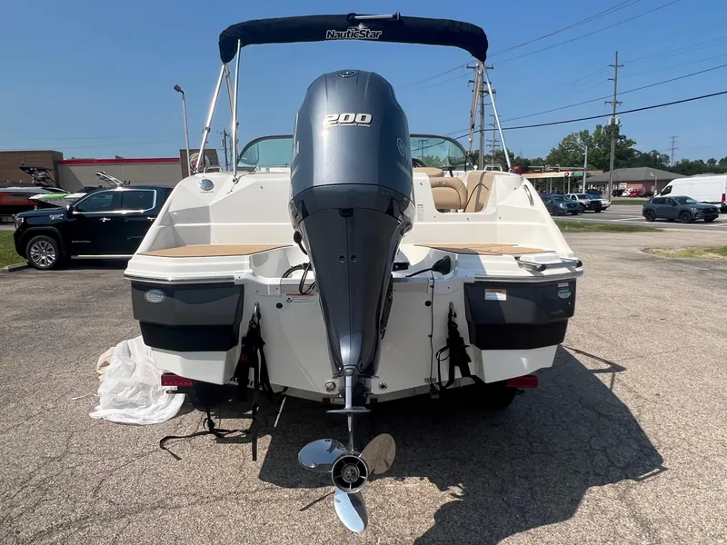 Slide: The Image of 2020 NauticStar 223 DC boat with 200 HP engine, parked outdoors. - 2