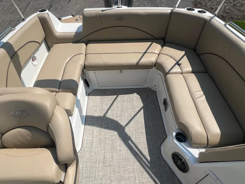 Slide: The Image of 2020 NauticStar 223 DC boat interior with beige seating and carpeted floor. - 6