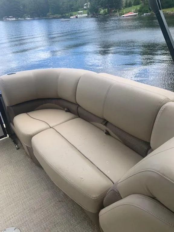 Slide: The Image of 2020 Regency 230 DL3 boat with beige seating by a serene lake. - 10