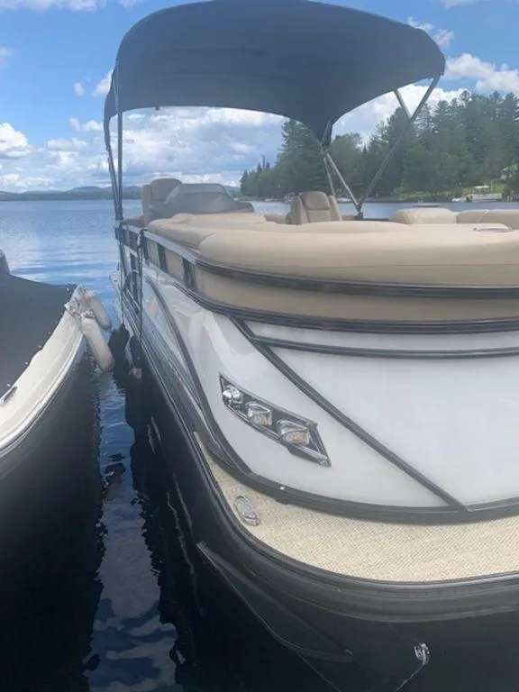 Slide: The Image of 2020 Regency 230 DL3 pontoon boat docked on a sunny lake. - 11