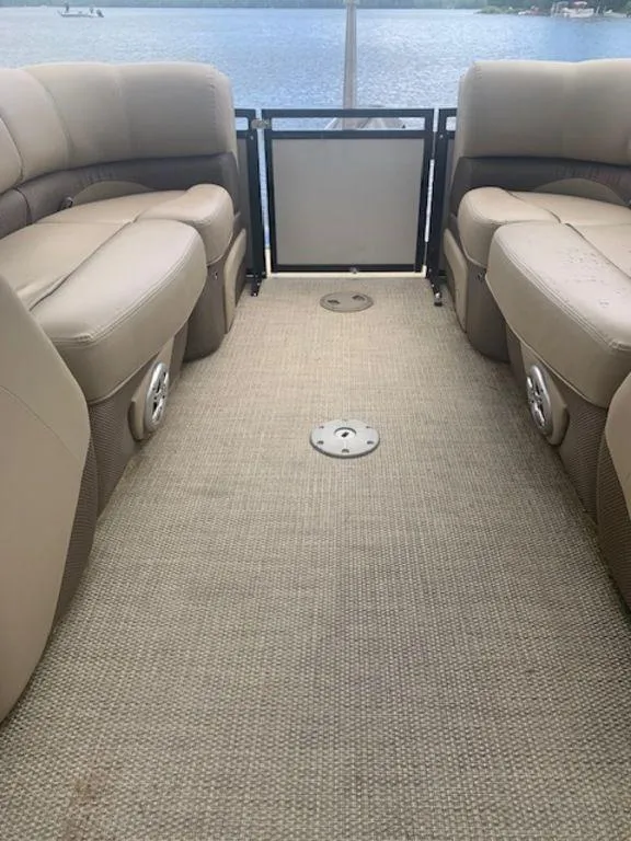 Slide: The Image of 2020 Regency 230 DL3 pontoon boat interior with beige seating and carpet flooring. - 21