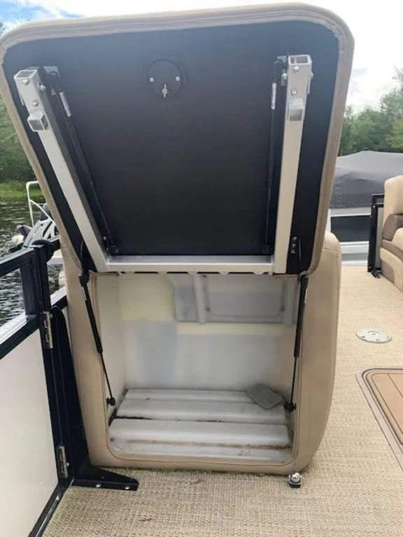Slide: The Image of Open storage compartment on 2020 Regency 230 DL3 boat, beige interior, lakeside view. - 28