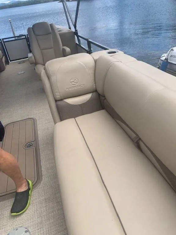 Slide: The Image of 2020 Regency 230 DL3 pontoon boat with beige seating on a calm lake. - 32