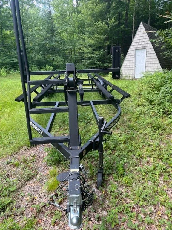 Slide: The Image of 2020 Regency 230 DL3 boat trailer in a wooded area near a small cabin. - 43