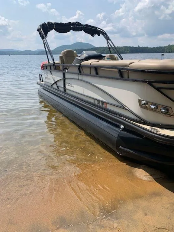 Slide: The Image of 2020 Regency 230 DL3 pontoon boat on a sandy lakeshore under a cloudy sky. - 5