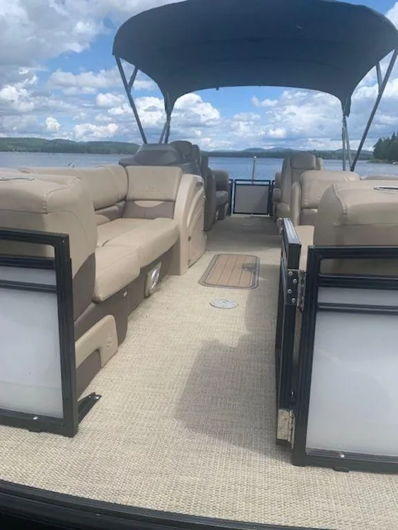 Slide: The Image of 2020 Regency 230 DL3 pontoon boat with beige seating and canopy on a lake. - 8