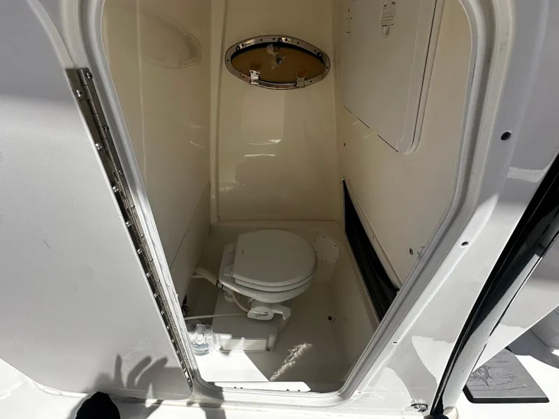 Slide: The Image of 2024 NauticStar 242 OSL boat interior bathroom with toilet and porthole. - 14