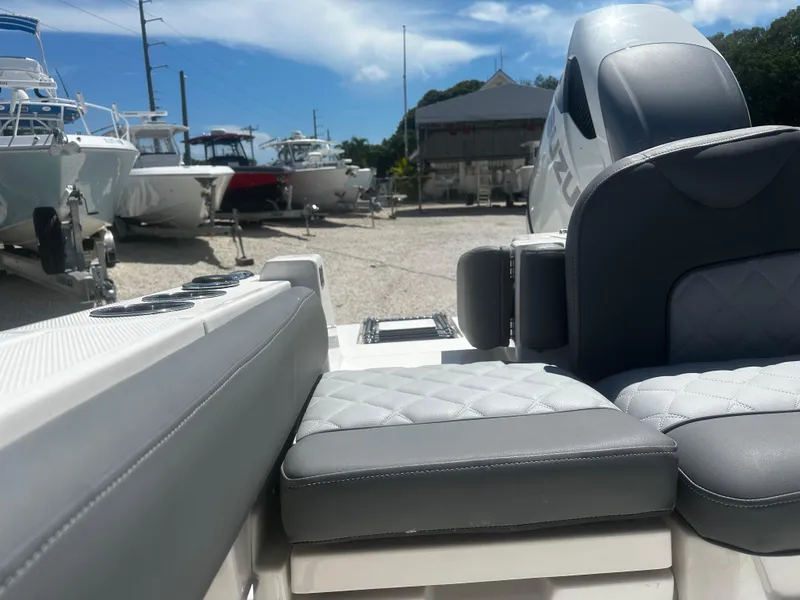 Slide: The Image of 2024 NauticStar 242 OSL boat interior with cushioned seating, parked among other boats. - 17