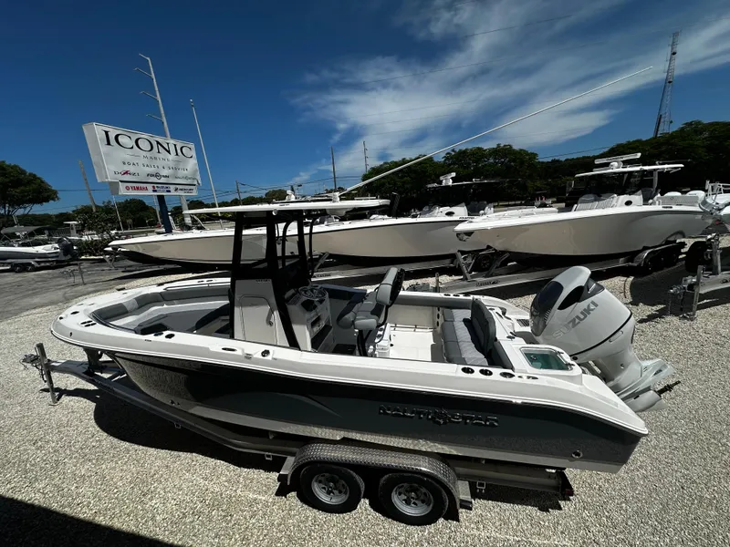 Slide: The Image of 2024 NauticStar 242 OSL boat on trailer at dealership under clear blue sky. - 19