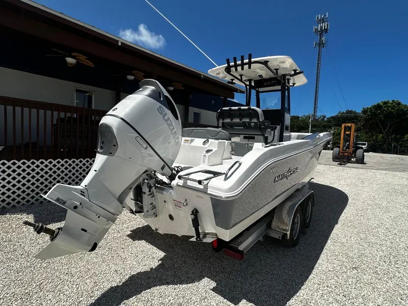 Slide: The Image of 2024 NauticStar 242 OSL boat with outboard motor on a trailer, parked outdoors. - 3