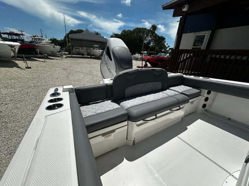 Slide: The Image of 2024 NauticStar 242 OSL boat interior with seating and storage, docked outdoors. - 4