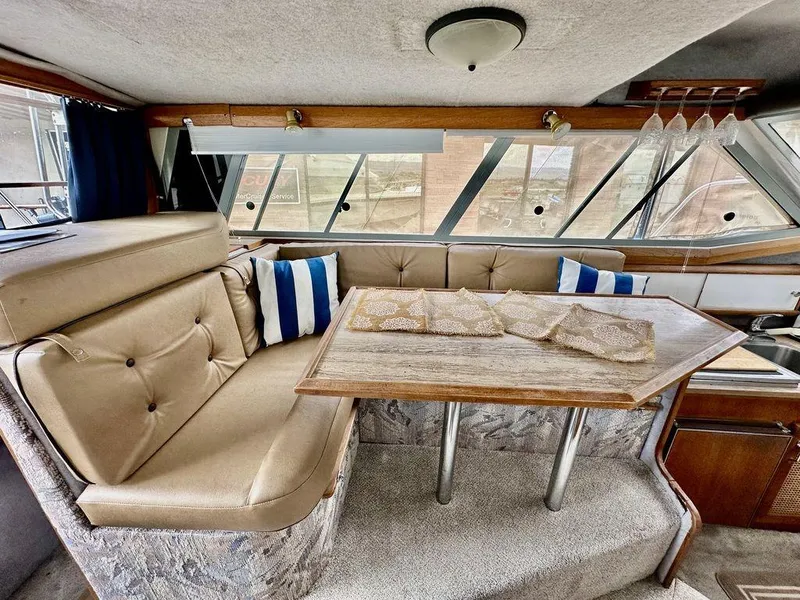 Slide: The Image of 1986 Bayliner 2850 Command Bridge interior with beige seating and wooden table. - 11
