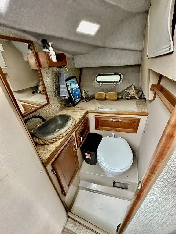 Slide: The Image of 1986 Bayliner 2850 Command Bridge bathroom with sink, toilet, and nautical decor. - 18