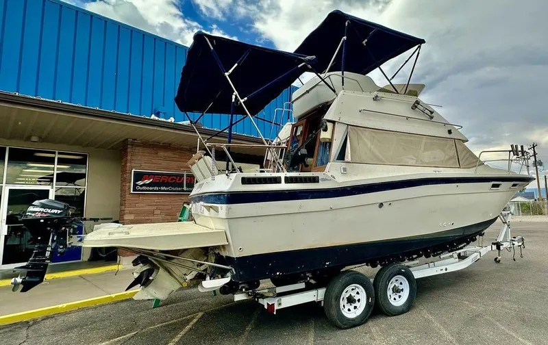 Slide: The Image of 1986 Bayliner 2850 Command Bridge boat on trailer, parked outside a marine dealership. - 4