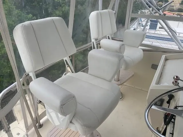 Slide: The Image of Helm seating on 1988 Hatteras 48 Convertible yacht, featuring white cushioned chairs. - 10