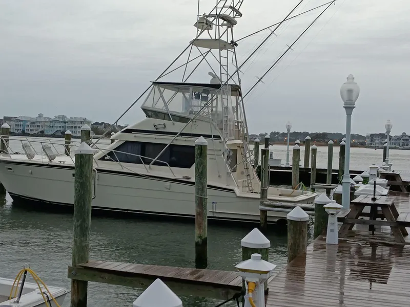 Slide: The Image of 1988 Hatteras 48 Convertible yacht docked at marina on a cloudy day. - 2