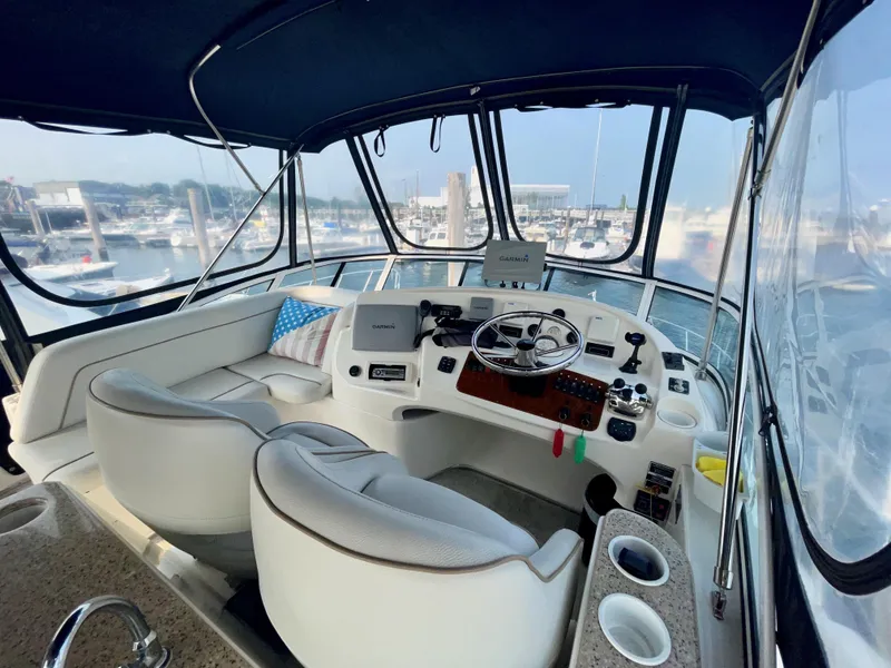 Slide: The Image of 2006 Silverton 43 Sport Bridge helm with marina view, featuring modern controls and seating. - 31