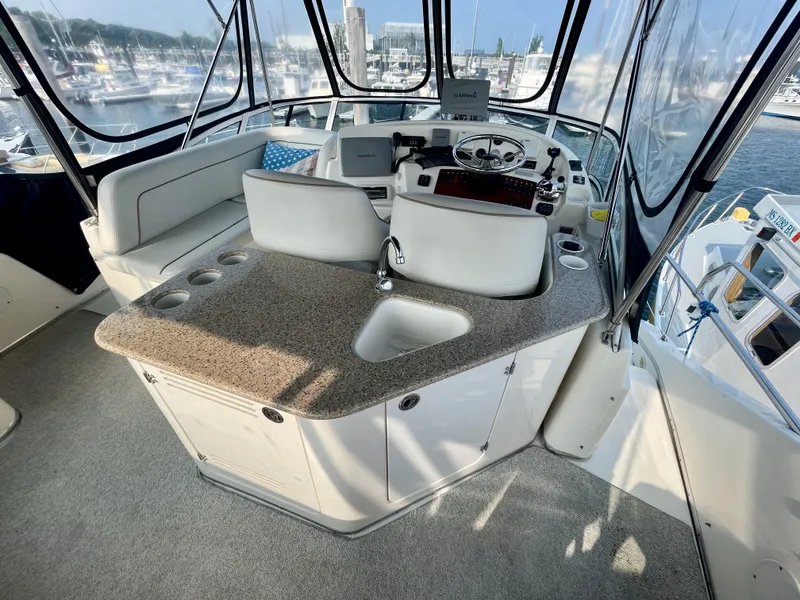 Slide: The Image of 2006 Silverton 43 Sport Bridge helm with seating, sink, and marina view. - 40
