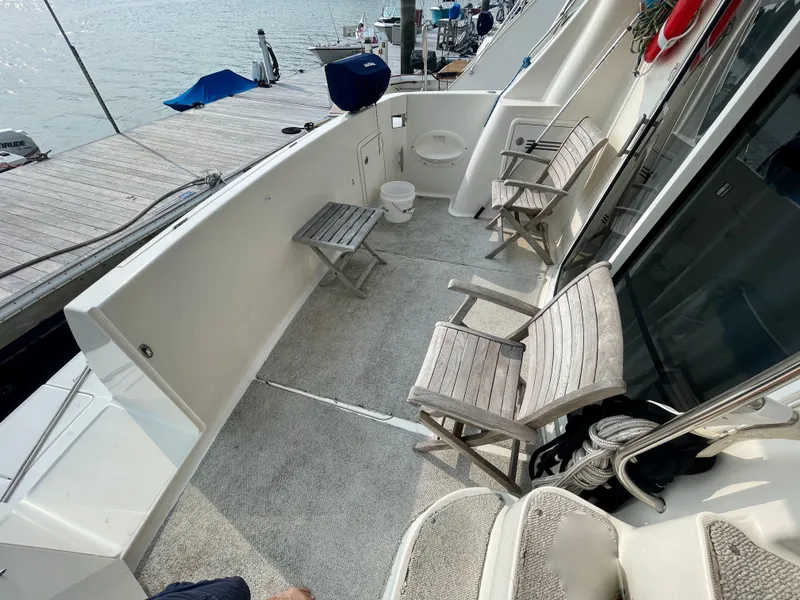 Slide: The Image of 2006 Silverton 43 Sport Bridge yacht deck with wooden chairs and marina view. - 45
