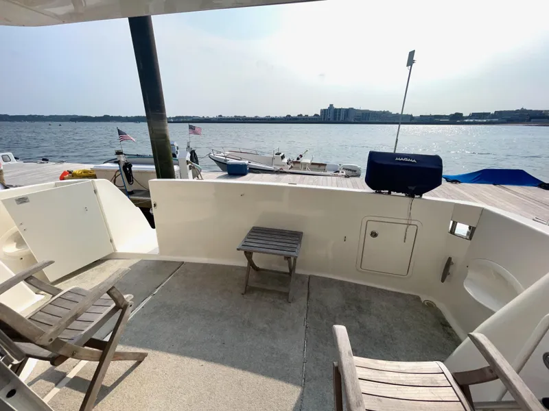 Slide: The Image of 2006 Silverton 43 Sport Bridge yacht deck with chairs, table, and waterfront view. - 46