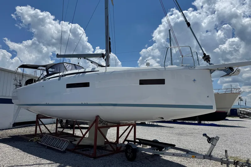 Slide: The Image of 2025 Jeanneau Sun Odyssey 380 sailboat on trailer under a cloudy sky. - 1