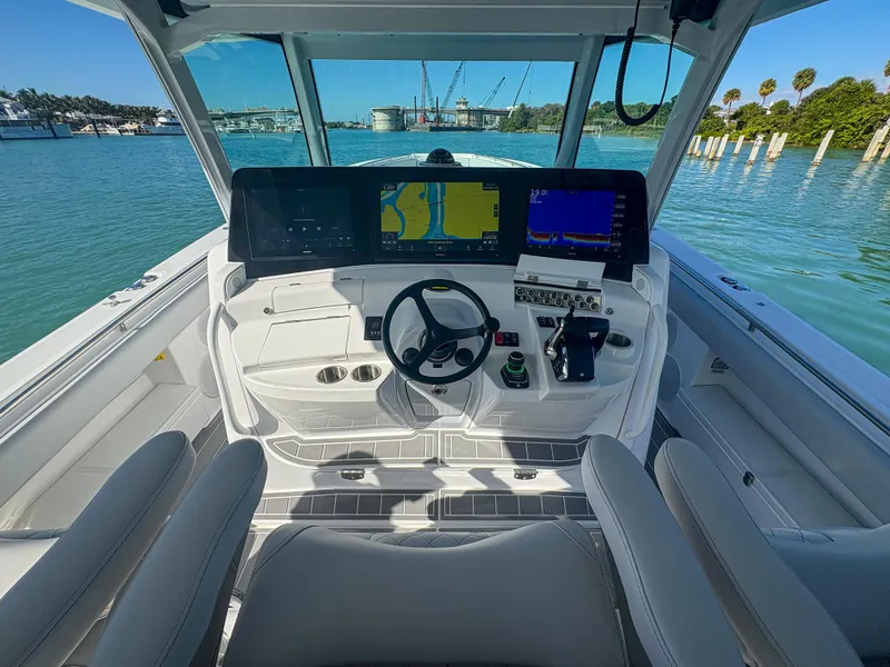 Slide: The Image of 2024 HCB 53' Suenos helm with advanced navigation screens on calm water. - 26