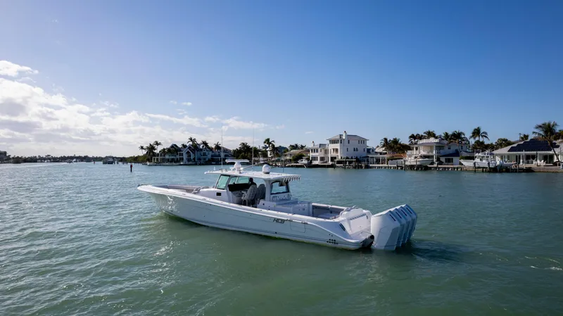 Slide: The Image of 2024 HCB 53' Suenos boat cruising on a sunny day near waterfront homes. - 6