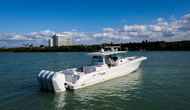 Slide: The Image of 2024 HCB 53' Suenos boat on calm water with a building in the background. - 8