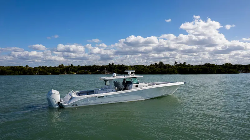 Slide: The Image of 2024 HCB 53' Suenos boat cruising on a calm lake under a partly cloudy sky. - 9