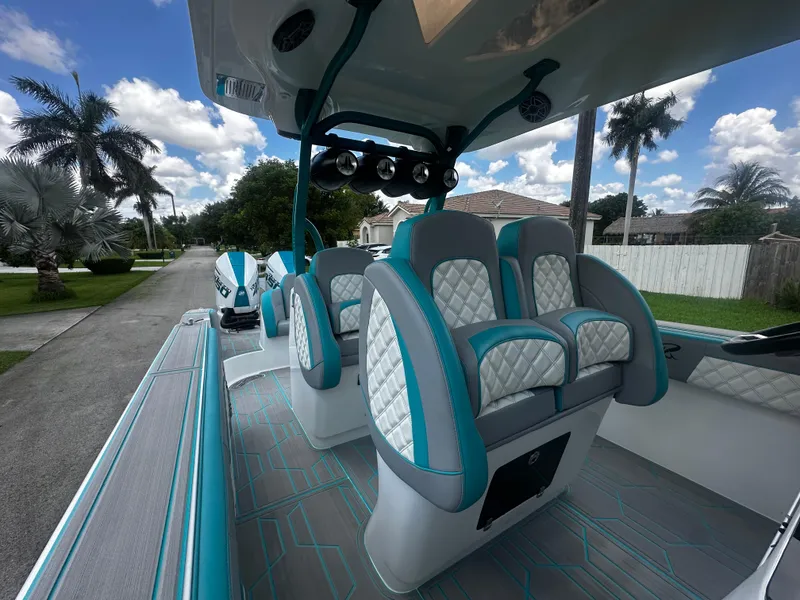 Slide: The Image of 2021 Renegade 38 Open boat interior with teal and white seating, palm trees in background. - 10