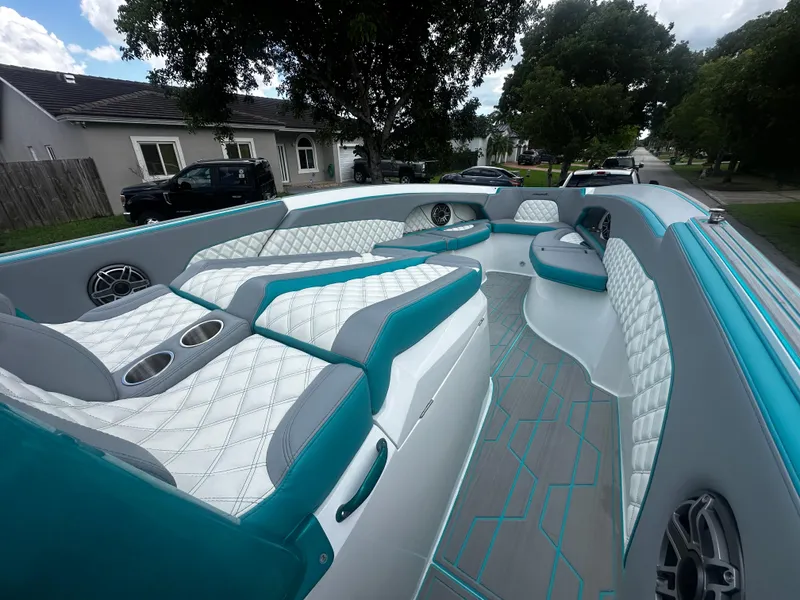 Slide: The Image of 2021 Renegade 38 Open boat with luxurious white and teal seating, parked in a residential area. - 23