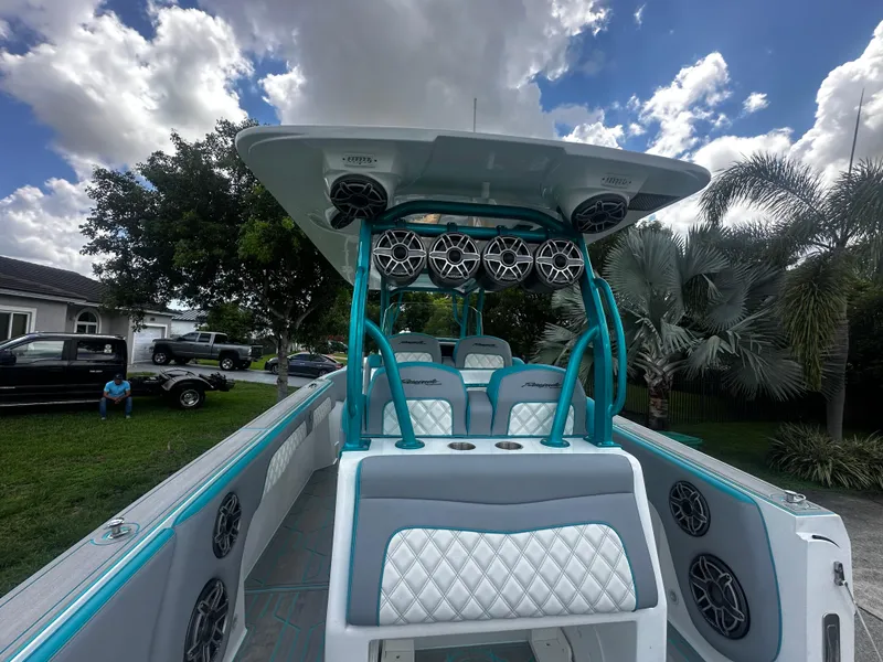 Slide: The Image of 2021 Renegade 38 Open boat with teal accents and premium seating under a cloudy sky. - 31