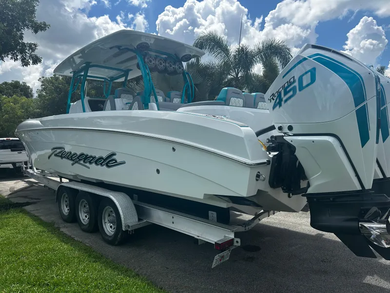 Slide: The Image of 2021 Renegade 38 Open boat on trailer, featuring twin engines, under a partly cloudy sky. - 33