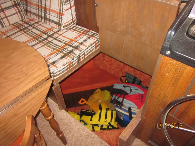 Slide: The Image of 1976 Harbor Master houseboat interior with storage compartment, plaid seating, and life jackets. - 3